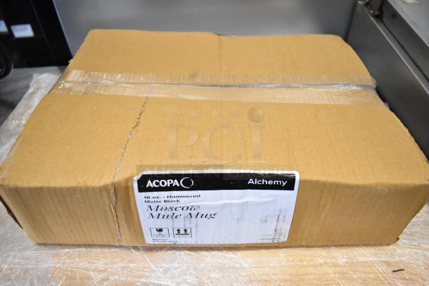 Box labeled "Acopa Alchemy 16 oz. Hammered Black Moscow Mule Mug," containing new mugs. Packaging shows signs of wear.