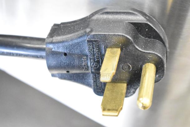 Plug of Avantco 177HWD10D 10 Gallon Hot Water Dispenser, 208/240V, 1 Phase. Black with gold prongs, close-up view.