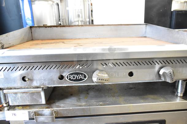 Royal stainless steel commercial gas-powered griddle, countertop model. Features adjustable knobs, worn cooking surface.