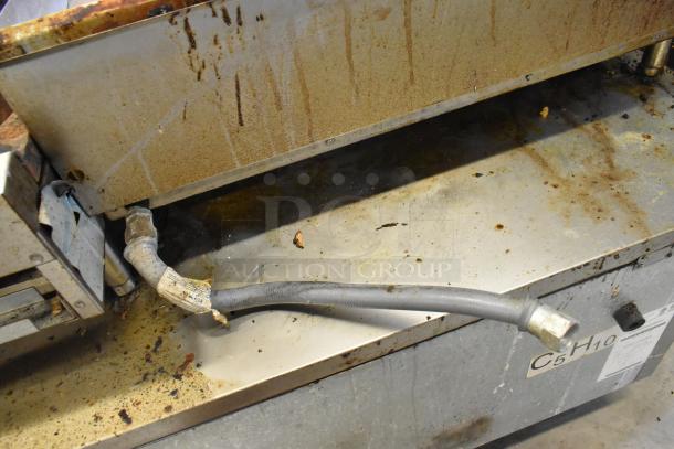 Royal Stainless Steel Gas Griddle, showing signs of use with grease marks. Visible gas hose and metal surface details.