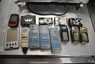15 assorted items including digital cameras, Garmin GPS units, and Hach colorimeters on a metal surface; various conditions.