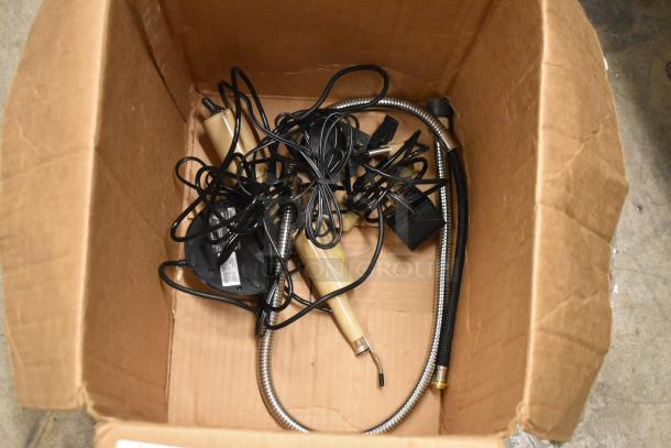 Box of miscellaneous electronics and cables, including digital cameras and tools, for auction. Condition varies.