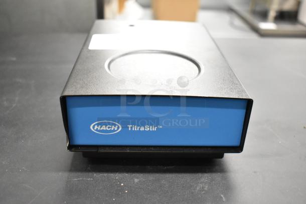 Hach TitraStir Stir Plate, 115 Volts, 1 Phase. Blue and black design, Hach logo visible. Appears in good condition.