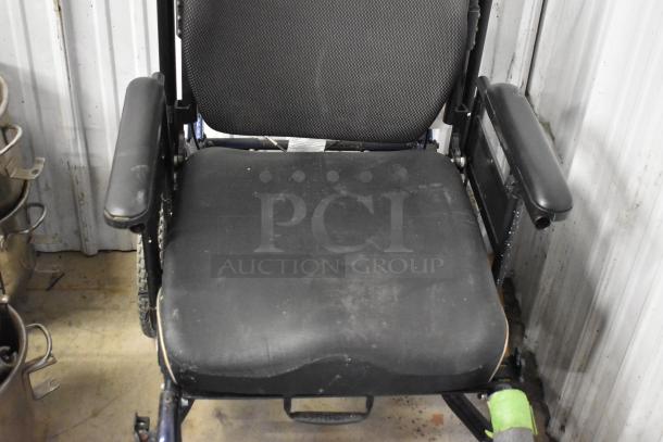 Comfort Ascent Wheelchair with padded seat, armrests, visible wear, and attached label. Interior setting.