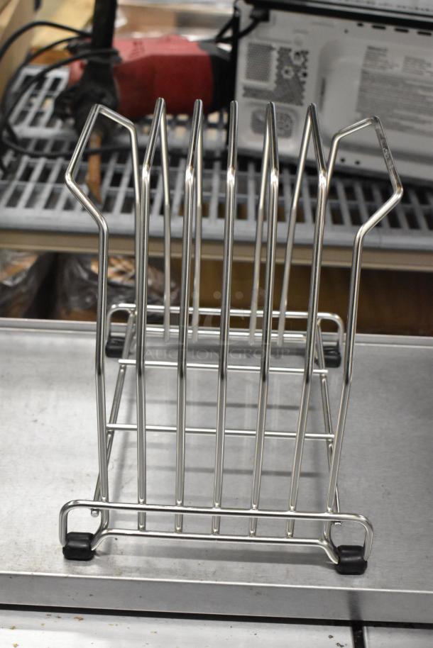 Metal drying rack with vertical bars and rubber feet on a metal surface. Good condition.