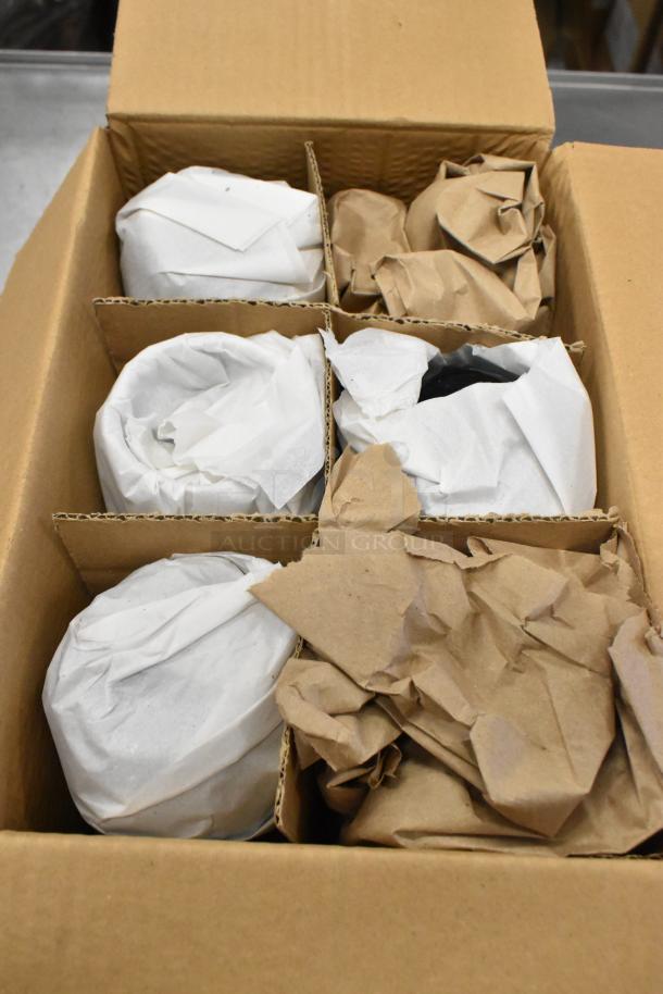 Box containing Acopa Pangea 15 oz. blue stemless wine glasses and Acopa Keystone 10 oz. granite gray stoneware creamers, wrapped in packing material.