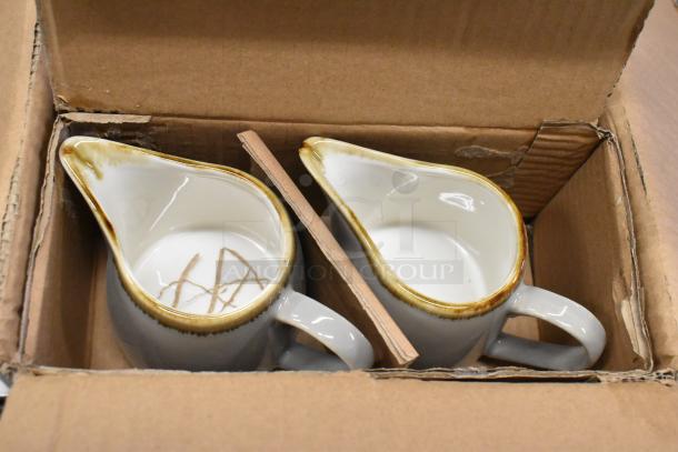 Two Acopa Keystone 10 oz. granite gray stoneware creamers in cardboard packaging, showing new condition.