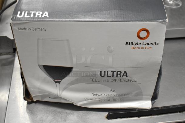 Box of Stolzle Ultra wine glasses, 16 oz, 6-pack. Box shows minor wear. Made in Germany, labeled "Feel the Difference."