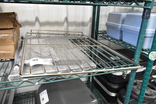 Four brand new scratch and dent items on a metal shelf, including an oven rack. Tags indicate lot 99.