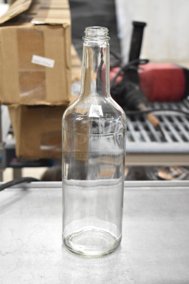 750 mL glass Bordeaux wine bottle, brand new, clear, with a classic design, standing on a metal surface.