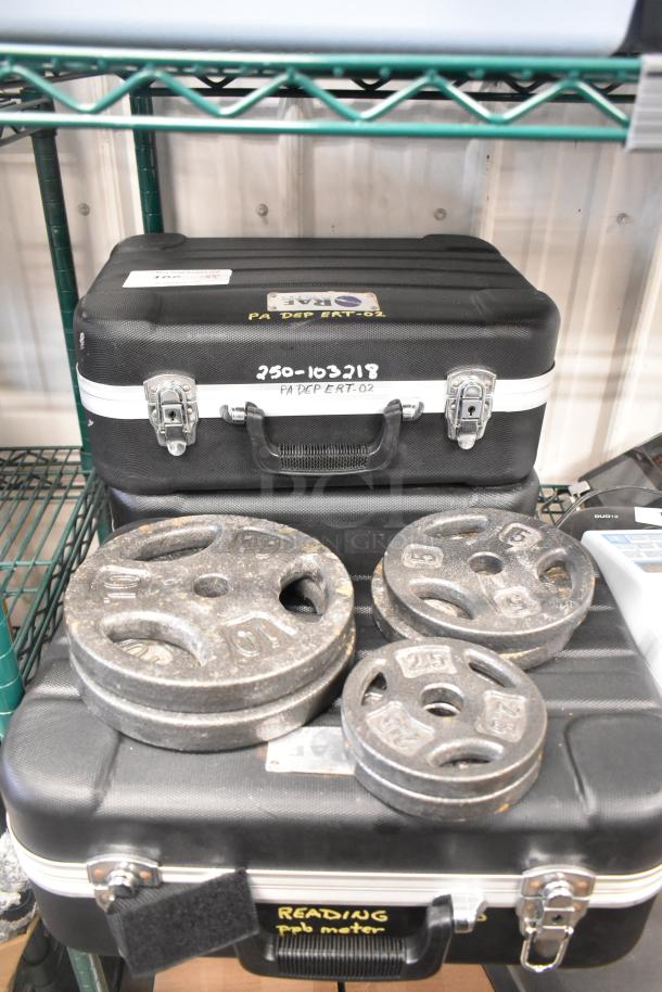 Nine-item auction set with weight plates in various sizes and two hard cases. Cases marked with "PA DEP ERT-02."