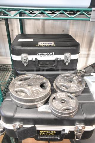 Nine-item auction set with weight plates in various sizes and two hard cases. Cases marked with "PA DEP ERT-02."