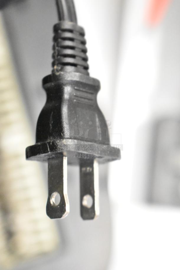 Close-up of a two-prong power cord plug, part of an auction including Hach meters, paper shredder, and card reader.