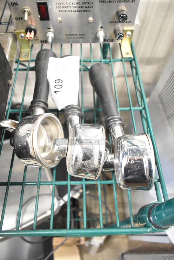 Three chrome portafilters with black handles, showing minor wear. Tag marked "109" is visible. Ideal for espresso machines.
