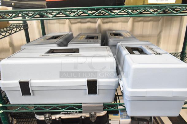 5 Hach 2100P Turbidimeter hard cases, empty, on a shelf. Light gray with locking clasps, durable design.