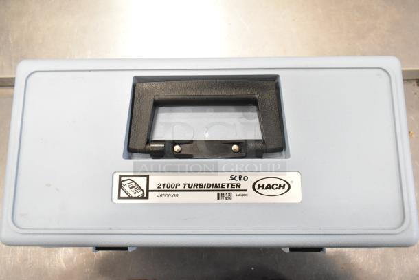 Blue Hach 2100P Turbidimeter hard case, empty, with black handle and label displaying model and serial number.