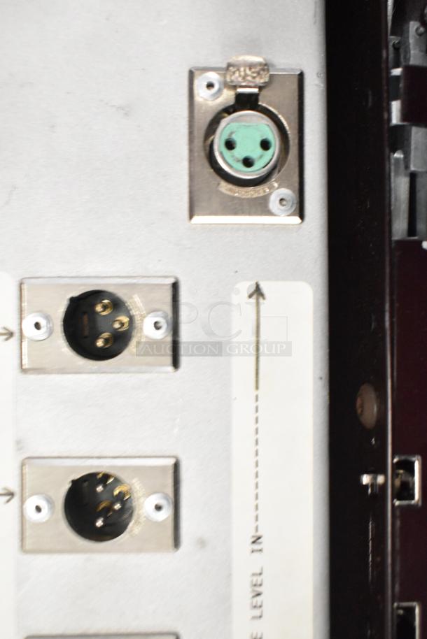 Close-up of metal ion meter connections. Includes circular port with green center and two round plug sockets with gold pins.