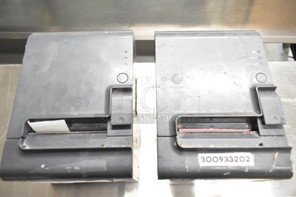 Two Epson M313A receipt printers, featuring visible wear. Includes a label with the number "300933202" on one unit.