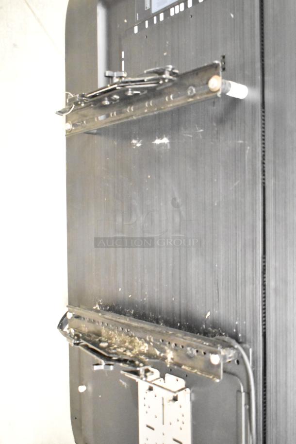 Back view of a Samsung PM49H 49" color display television with wall mounting brackets attached. Visible wear and dust.