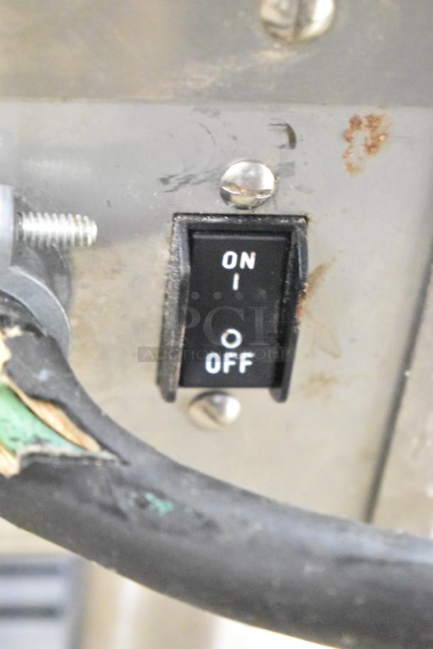 Close-up view of the on/off switch of a Bunn IMIX-5 stainless steel cappuccino machine, showing slight wear.