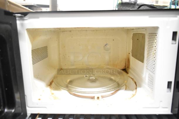 Countertop microwave oven, model MSF0B100072352, with glass plate. Runs on 120 volts, 1 phase. Interior shows signs of wear.