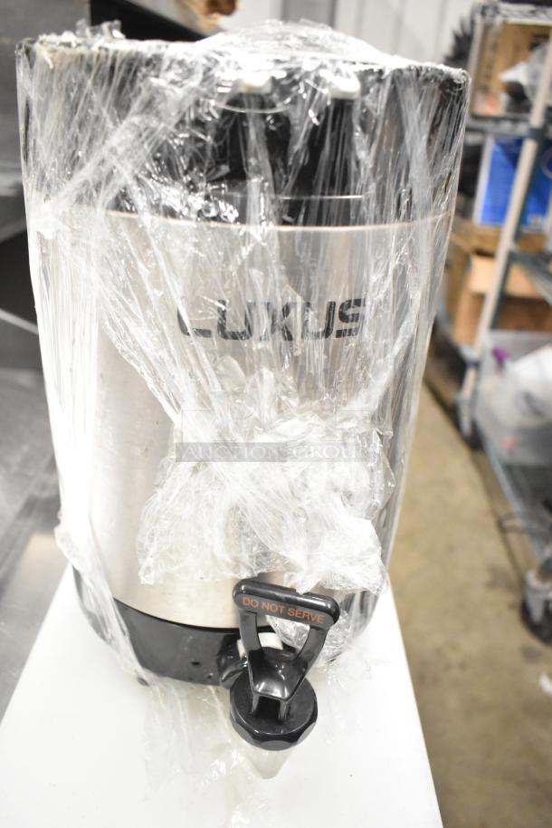 LUXUS beverage dispenser wrapped in plastic, labeled "DO NOT SERVE," part of a mixed auction lot including rice cooker inserts.