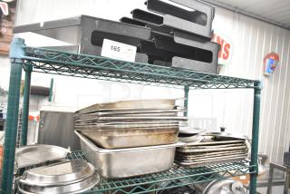 Two-tier lot with stainless steel drop-in bins, metal pans, and lid organizers on a metal rack. Auction tag reads "165".