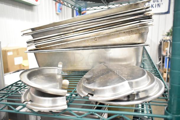 Two-tier lot of stainless steel drop-in bins, metal pans, and lid organizers on a wire rack, used condition.