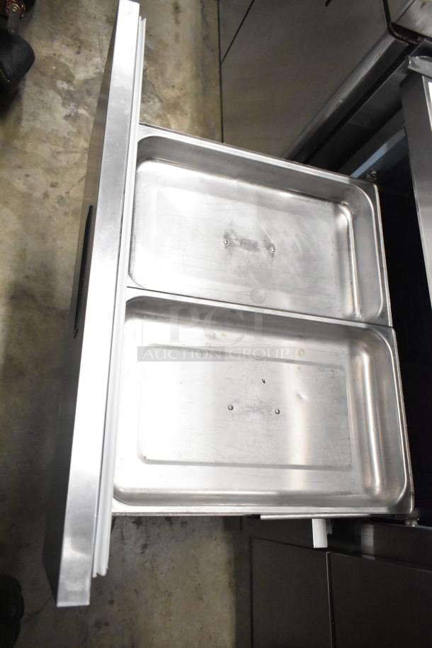 Delfield UCD4464N-12-DD5 stainless steel prep table with open drawer, showing storage pans. Commercial casters visible.