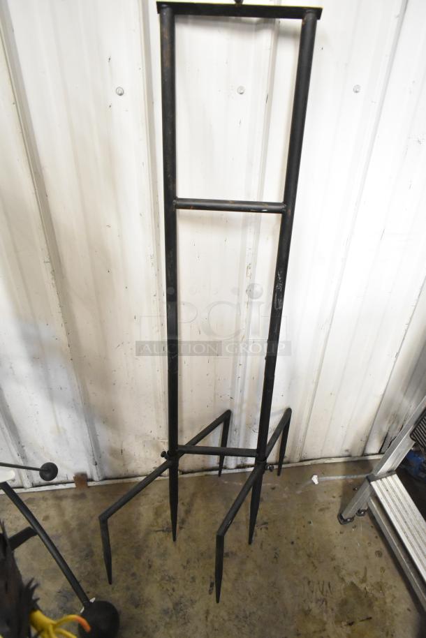 Decorative iron stand for eagle display, black finish, in used condition, featuring a sturdy four-legged base.