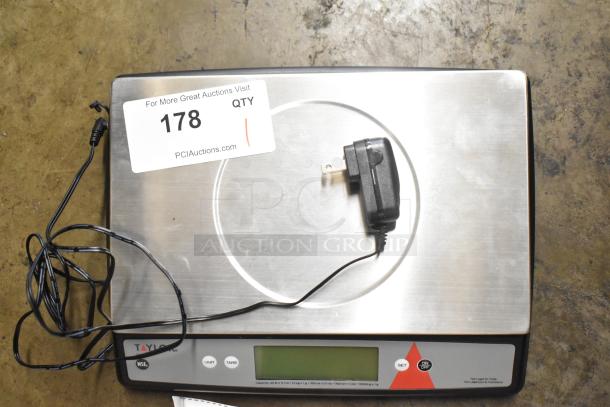 Taylor TE22OS countertop scale with digital display and power adapter; stainless steel surface; auction tag visible.