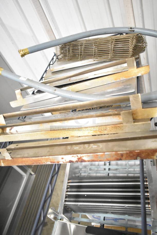 Nine assorted metal pieces, including a rusted conveyor belt, hoses, and industrial components, on a metal shelf.