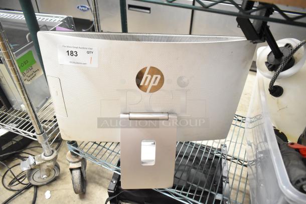 HP All In One Desktop, rear view showing HP logo. Auction tag 183 present. Mounted on adjustable stand.