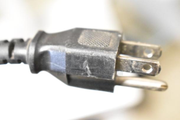Close-up view of a plug from an HP All In One Desktop, showing a standard two-prong power connector.