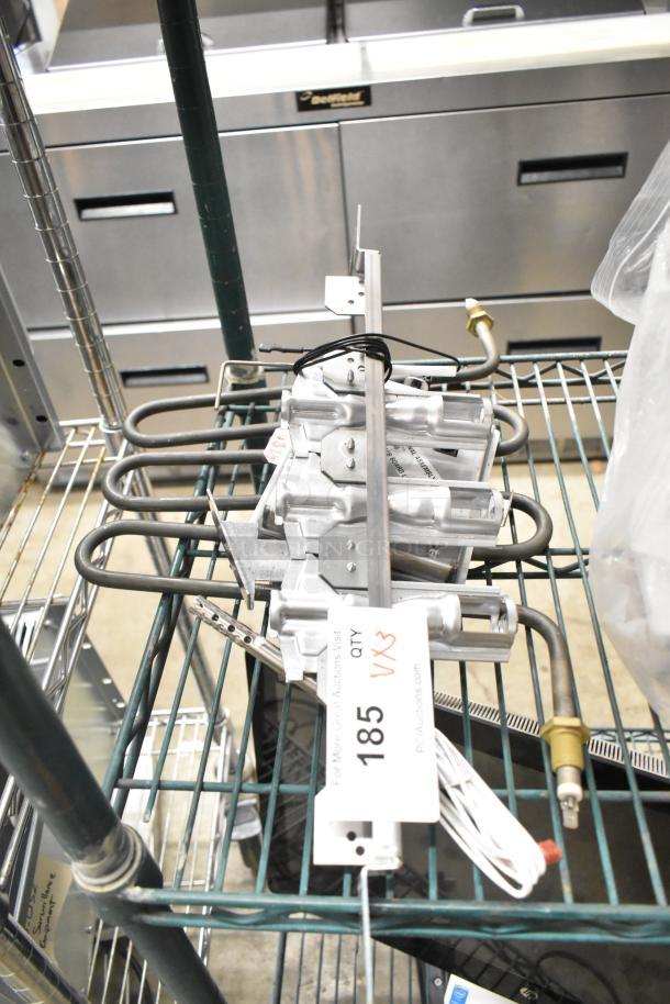 Three various metal items including a burner, with a tag labeled "185 VX3," on a wire rack.