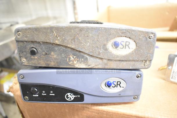 Two QSR kitchen controllers showing signs of wear, featuring power and activity indicators, on/off switch, and QSR logo.