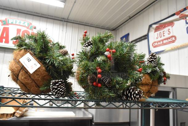 Three decorative fake plants with pine needles, red berries, and pinecones in coco fiber baskets. Auction lot tag: 192, Qty: 3.