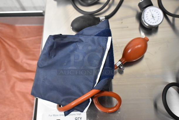 Four assorted blood pressure cuffs, varied colors, with gauges and bulbs. Slight wear visible. Auction includes four items.