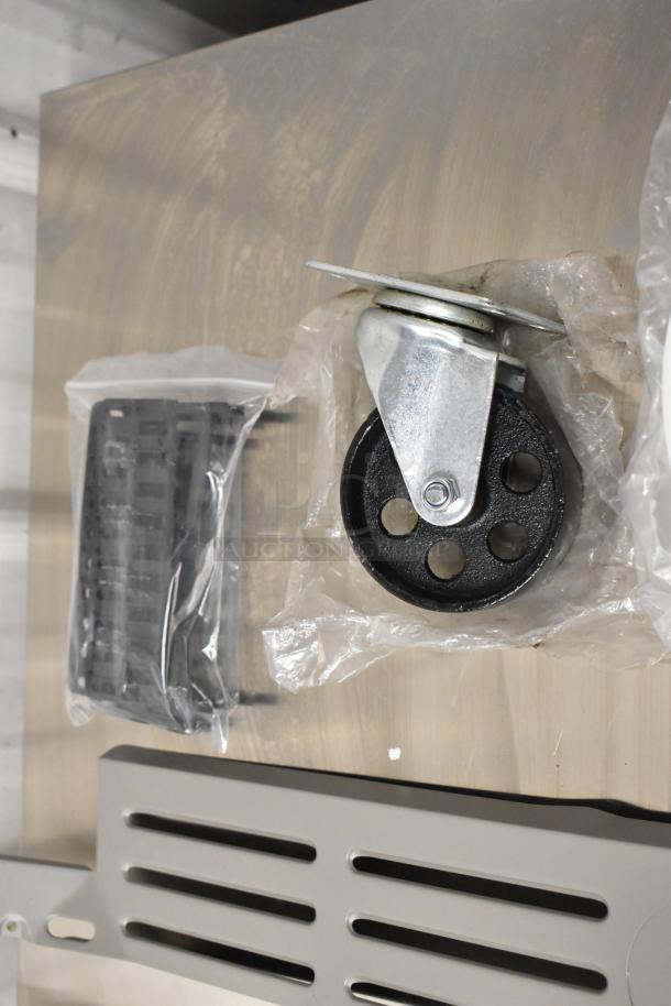 Five assorted items including a metal caster, black panels, and a slotted metal component, mostly in packaging.