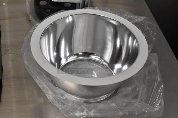 Shiny metal bowl on plastic wrap, part of a lot with casters and panels. Bowl in new condition, reflecting surroundings.
