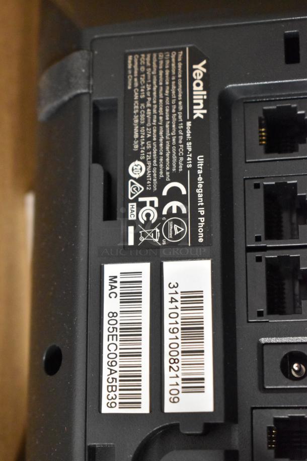 Close-up of a Yealink IP phone model SIP-T41S, featuring labels for MAC address and serial number, with network ports visible.