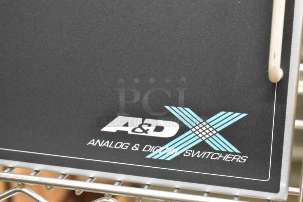 Analog & Digital Switchers A&D Unit, black panel, A&D logo, blue X design, steel frame.
