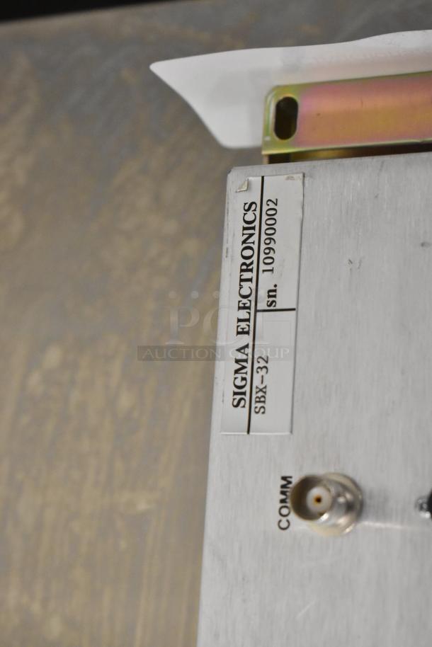Sigma Electronics SBX-32 switcher, metal casing, serial number 10990002, COMM port visible, good condition.
