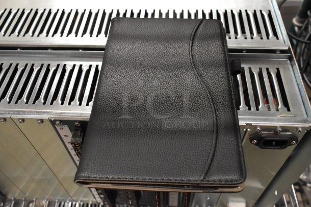 Alt Text: Black textured case atop Avigilon VMA-ENVR1-8P8 Embedded NVR, showing metal casing and port details.