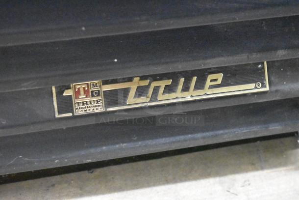 True GDM-41SL-60-LD nameplate on commercial cooler. Gold logo on black background indicates True Manufacturing.