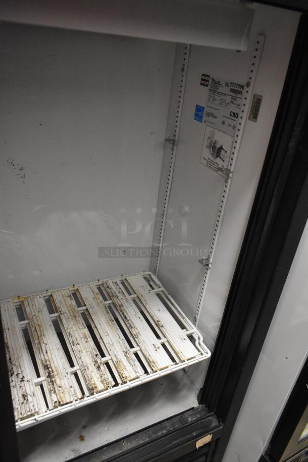 True GDM-41SL-54-LD 2-door cooler merchandiser with poly coated racks, showing wear. 115 volts, 1 phase. Labels visible inside.