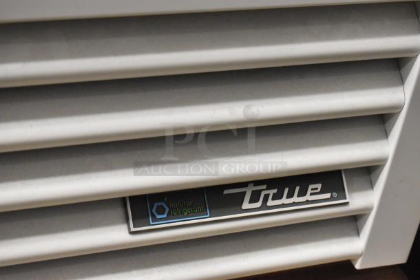 2021 True TSCI-600R-G-PH reach-in cooler logo detail, featuring natural refrigerant label on metal louvered panel.