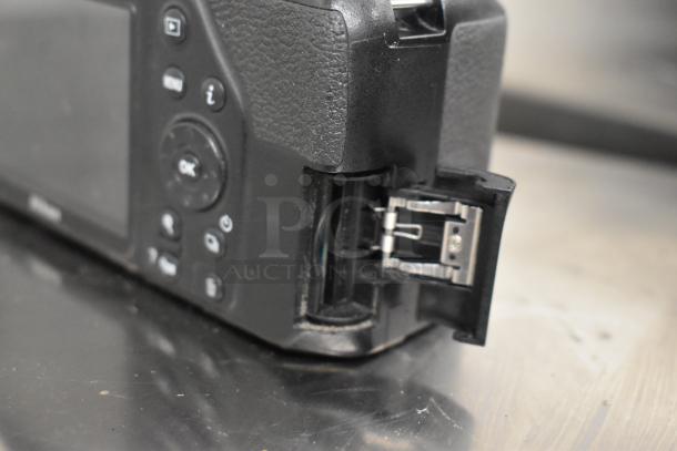 Nikon D3500 digital camera body, no lens, shown with open battery compartment. Buttons and textured grip visible.