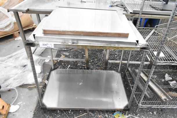 Stainless steel table with under shelf, used condition, visible wear and some rust. Label indicates quantity 235.