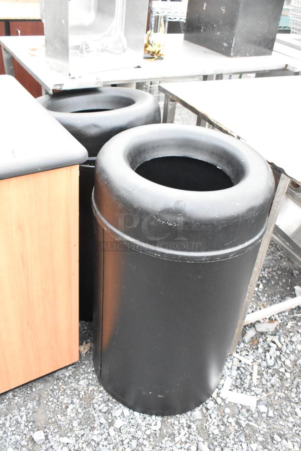 Three trash can shells: two black, one wood-patterned. Durable construction, urban setting. Condition: used.